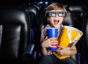 Surprised boy holding snacks while watching 3D movie in cinema theater