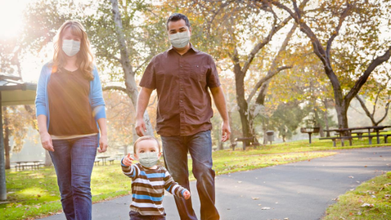 family with facemasks walking down road